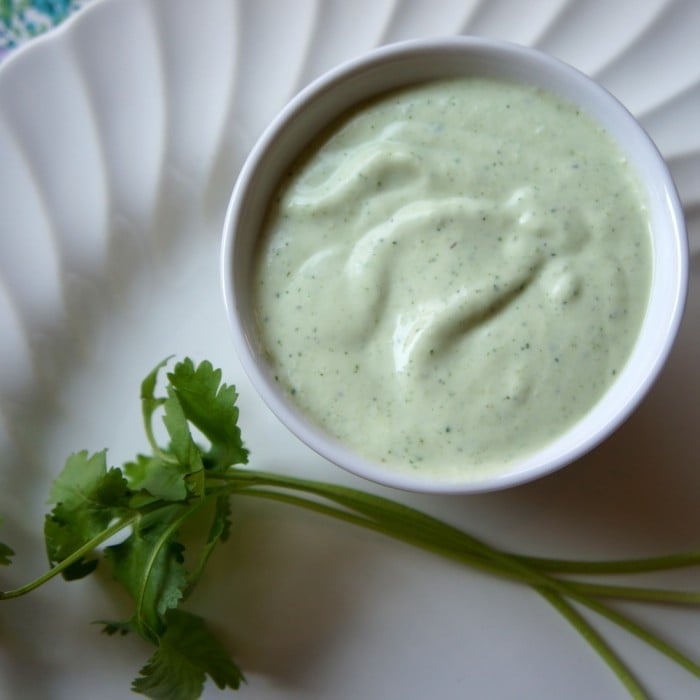 Close up of a small bowl of green salad dressing on a plate