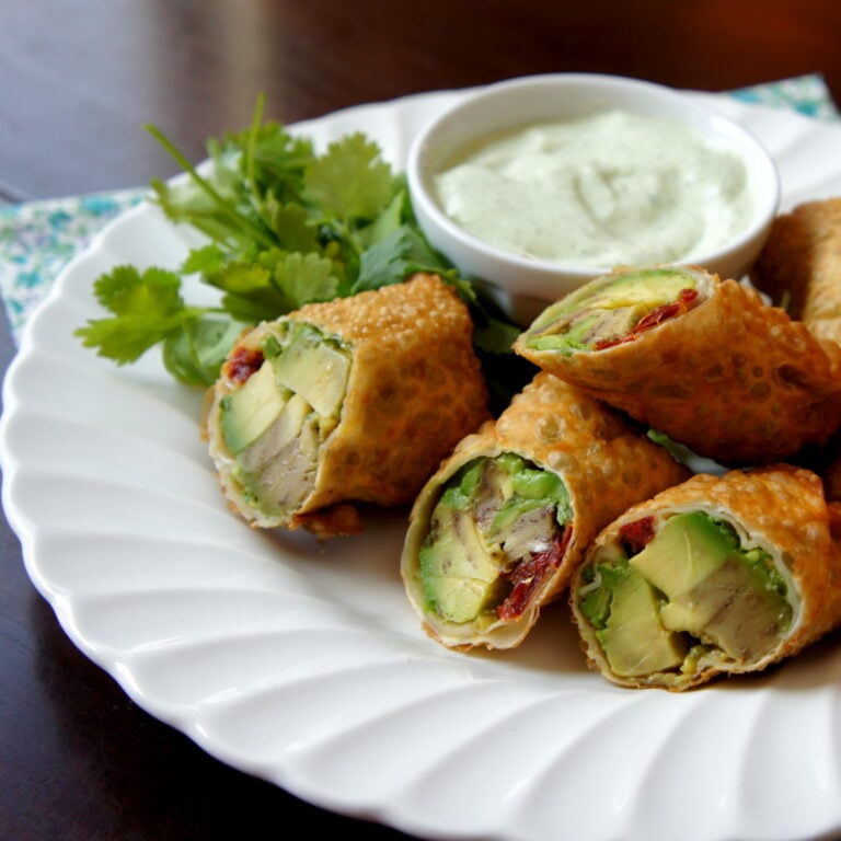 Veggie egg rolls cut in half with a side of dip