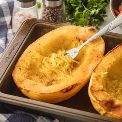roasted spaghetti squash in pan with fork.