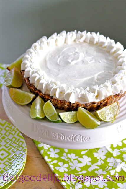 A close up a of a No Bake Key Lime Pie topped in a white topping and sliced limes  on the side