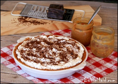 English Banofee pie  on top of a red checkered cloth next to a jar of caramel