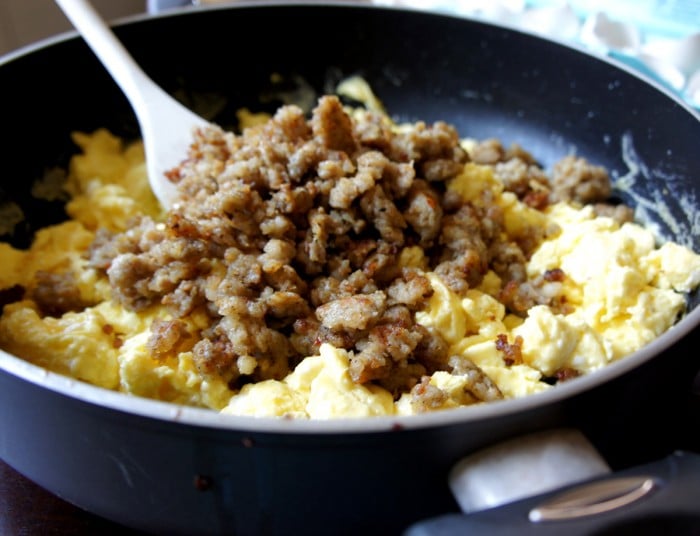A pan cooking scrambled eggs and sausage