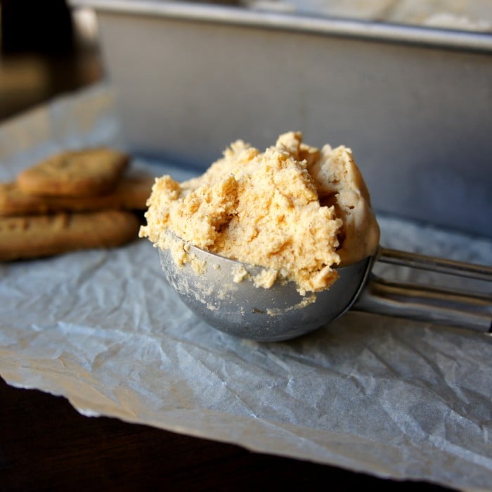 A close up of an ice cream scooper filled with a scoop of ice cream on a table 