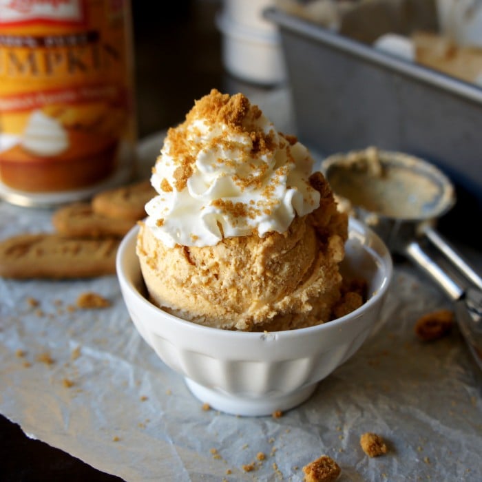 A scoop of Pumpkin Cheesecake Ice Cream in a bowl topped with whipped cream