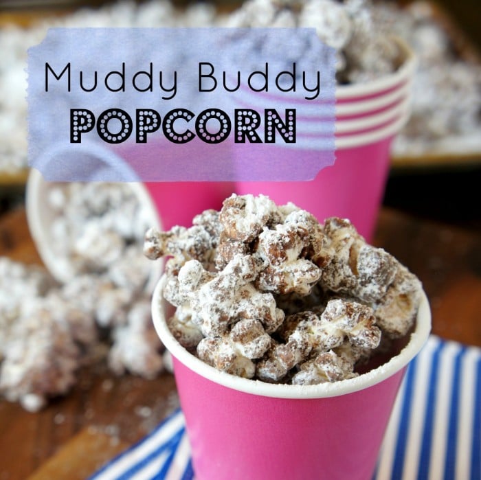 A pink cup full of Muddy Buddy Popcorn in front of other filled pink cups