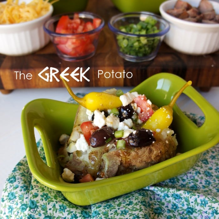 A baked potato on a green plate with a Greek themed potato bar toppings