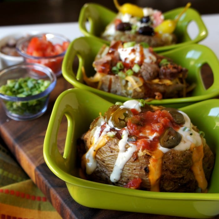 Three plates with a baked potato on each with a variety of toppings