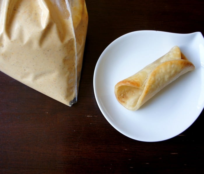 An empty cannoli shell next to a bag of pumpkin pie filling