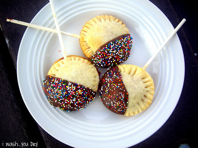 Three chocolate covered mini pie pops dipped in sprinkles on a plate