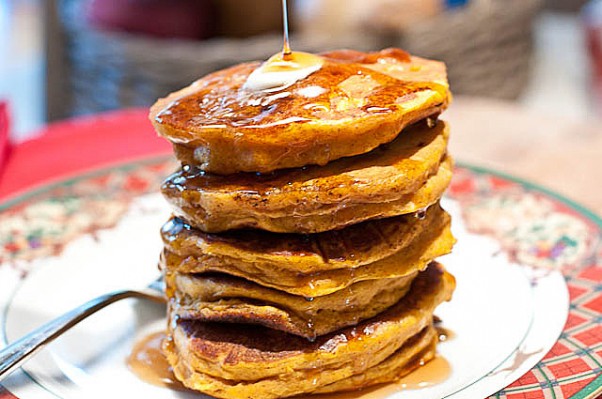 A stack of pancakes with syrup being poured on top