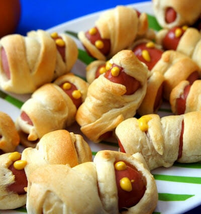 Mini Mummy Wrapped Hot Dogs on a plate with mustard eyeballs