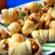 Mini Mummy Wrapped Hot Dogs on a plate with mustard eyeballs