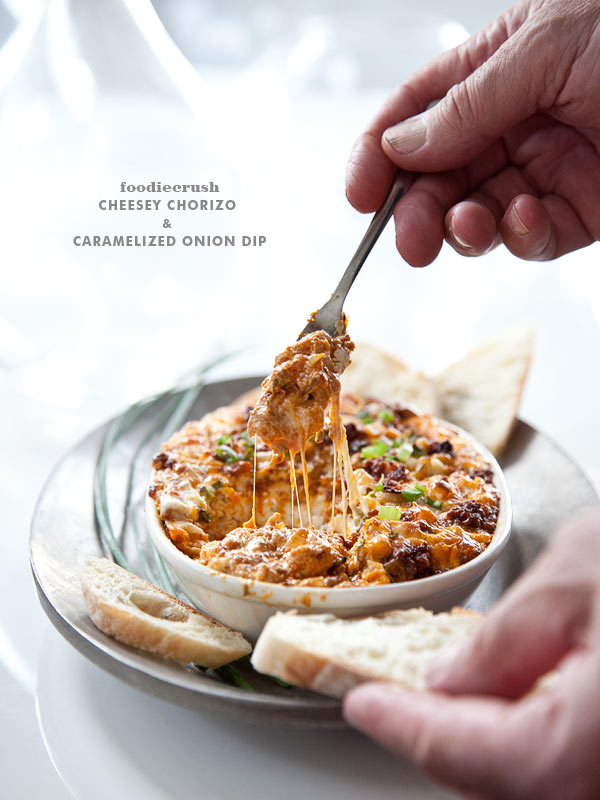 A hand removing some of the Chorizo Cheese Dip from a small dish of dip on a table 