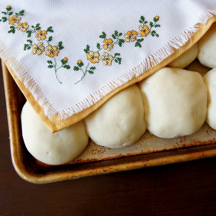 A pan of raising dough balls covered by a towel