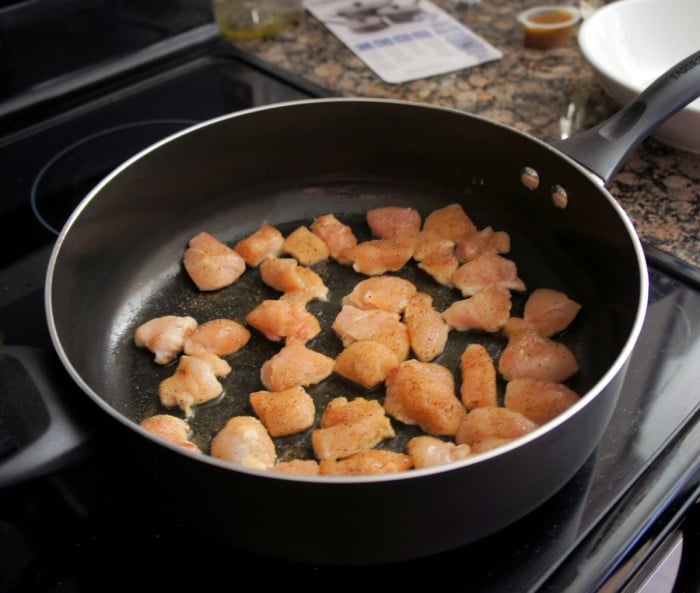 A pan cooking the cut up chicken pieces