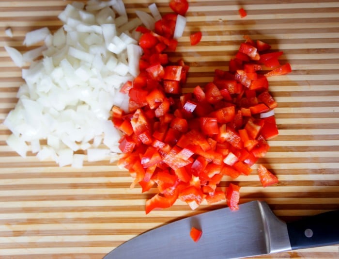 A cutting board with chopped onions and peppers