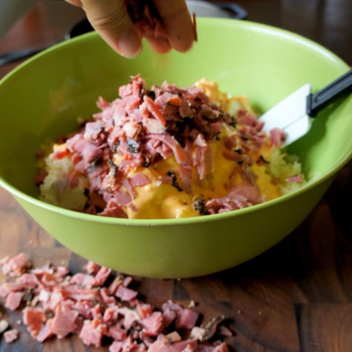 A bowl of ingredients to make dip topped with chopped pastrami 