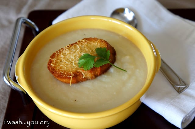 A bowl of white cream based soup with a toasted piece of bread on top