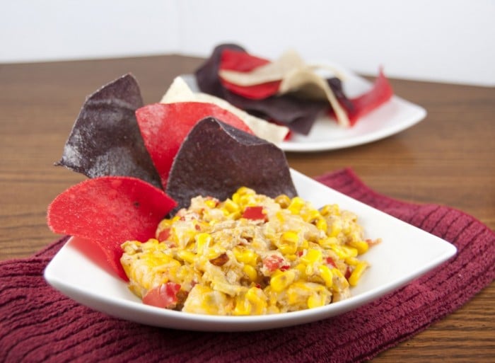 Red and black chips next to a bowl of Hot Corn Cheese Dip