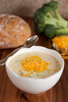 A bowl of white cream base soup topped with orange shredded cheese