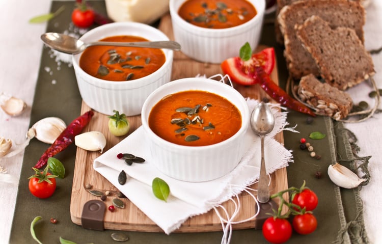 Three small bowl of tomato soup topped with fresh herbs