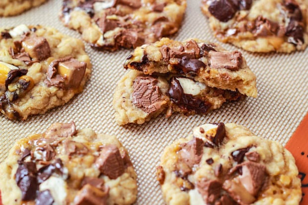 A close up of cookies on a baking pan made with chocolate chips  and halloween candy