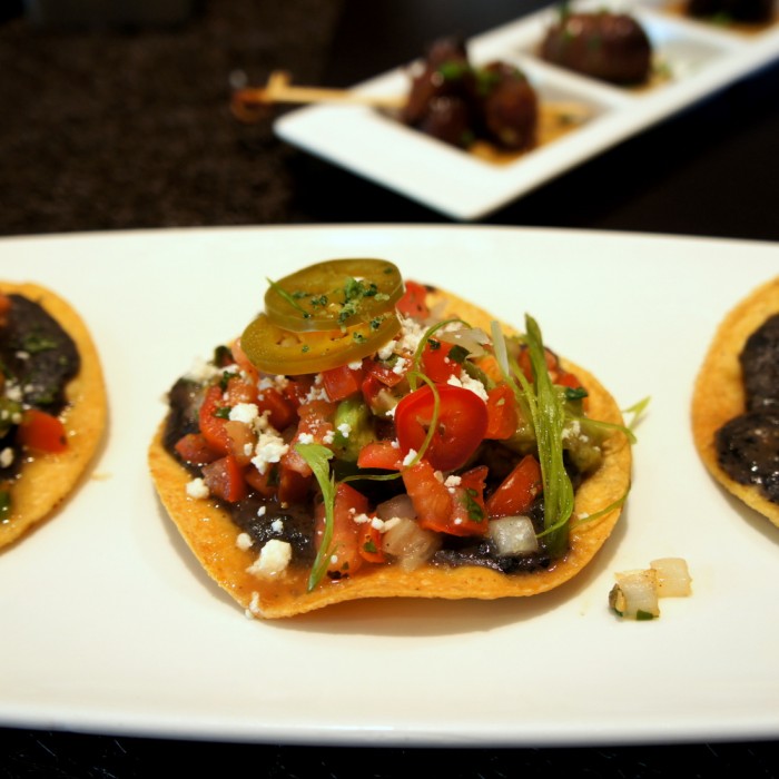 A close up of bean dip displayed on a chip on a plate