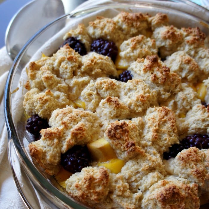 A close up of a round glass dish with Mango and Blackberry Cobbler in it. 