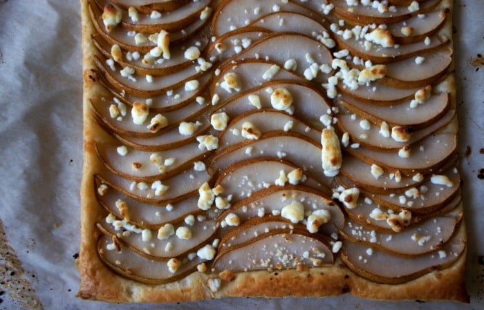 A close up of the top of a Pear Tart with goat cheese sprinkled on top of it