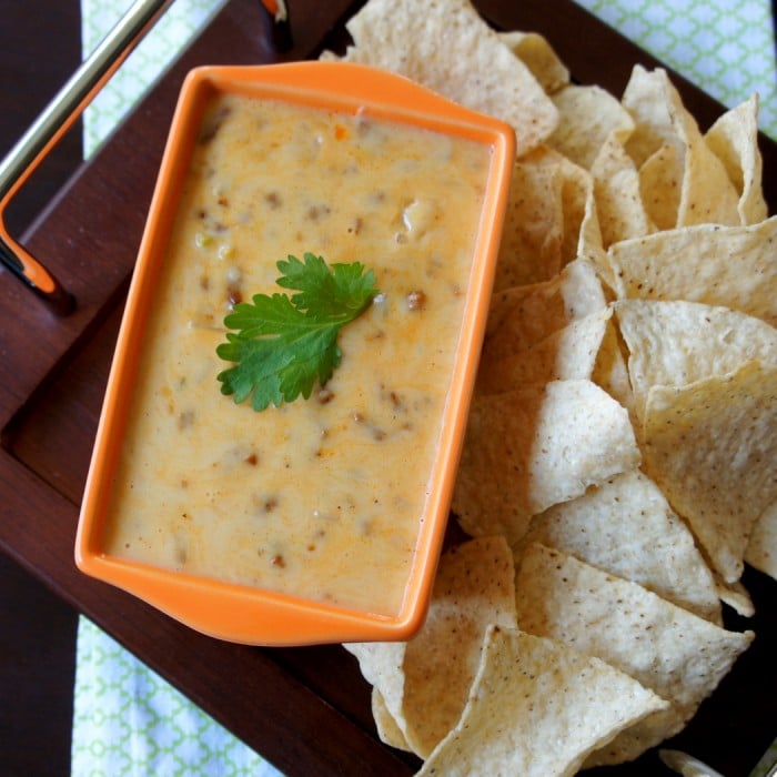 A look down on a small bowl of cheese dip with a side of chips