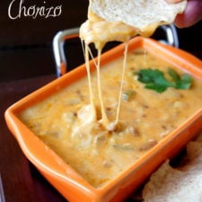 A hand dipping a chip in a cheesy sauce titled, "Queso Fundido with Chorizo"