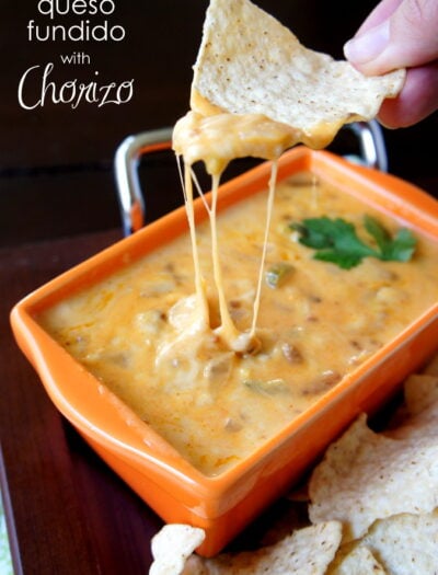 A hand dipping a chip in a cheesy sauce titled, "Queso Fundido with Chorizo"