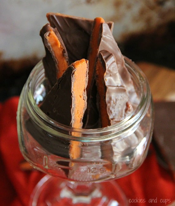 Pieces of Homemade Butterfinger Bark in a glass cup