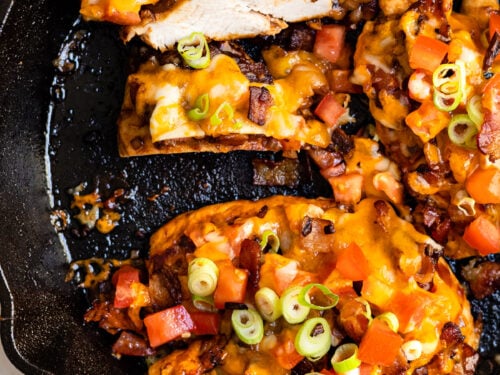 black skillet with cheese and bacon covered chicken breast.