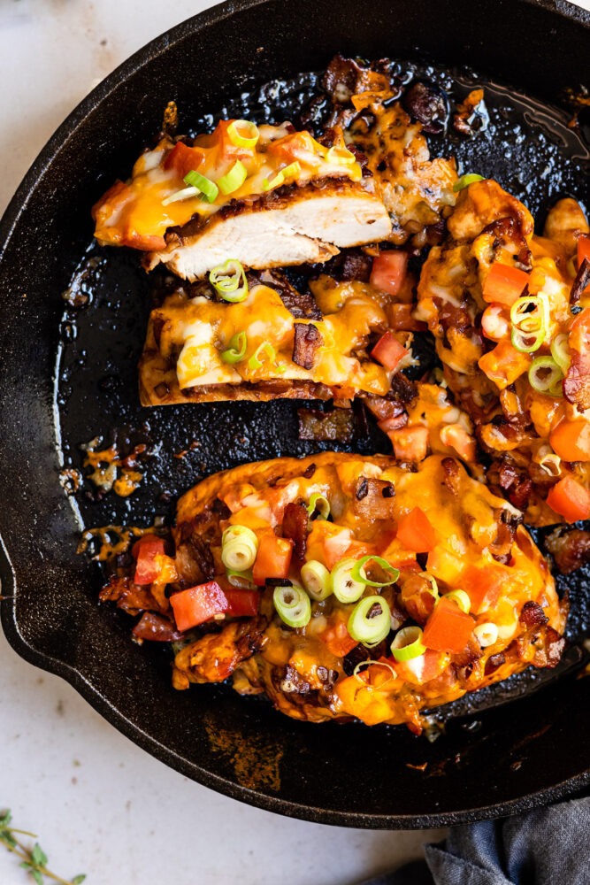 black skillet with cheese and bacon covered chicken breast.