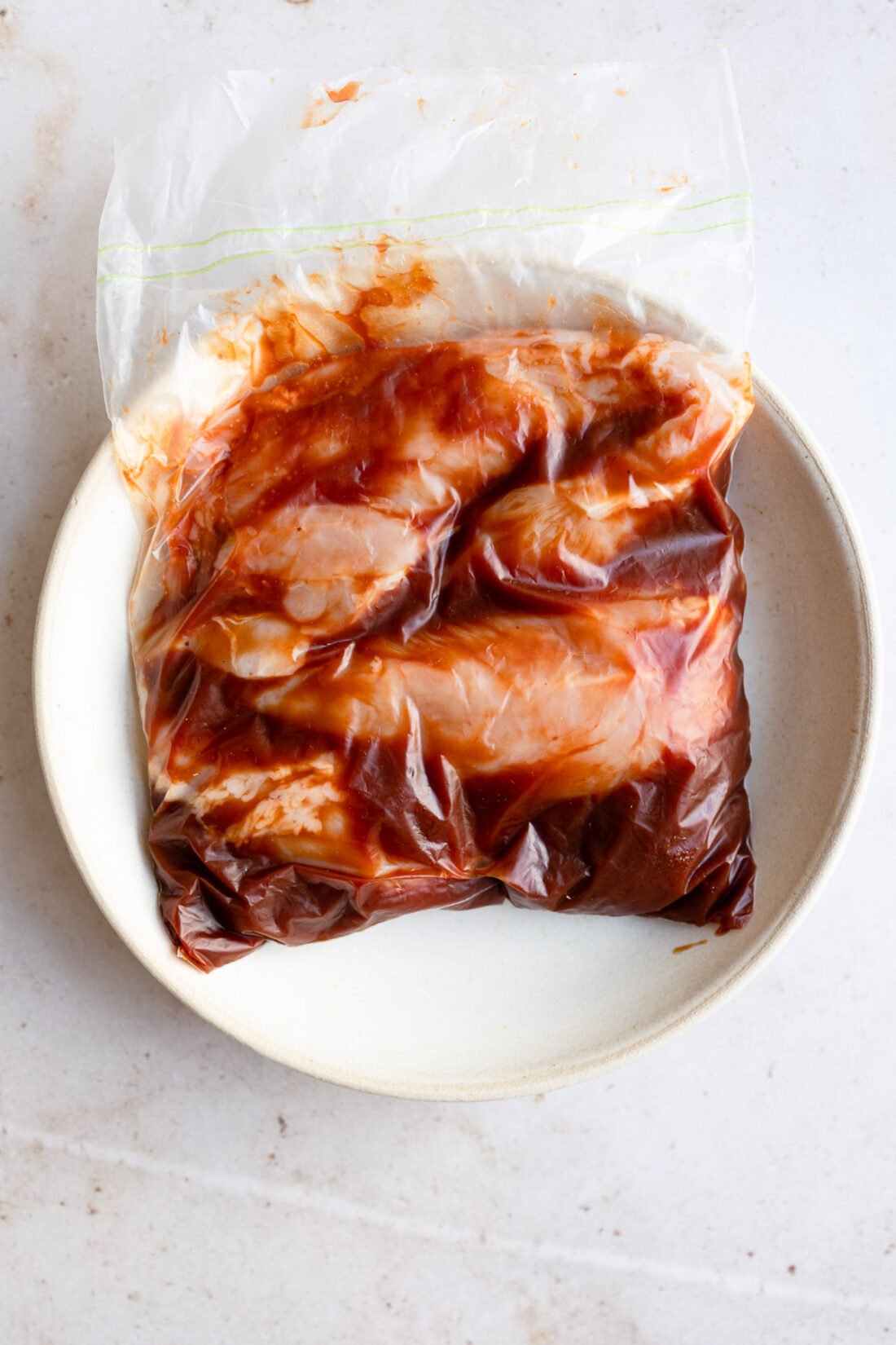 bbq sauce covered chicken breast in zip close bag for marinating.
