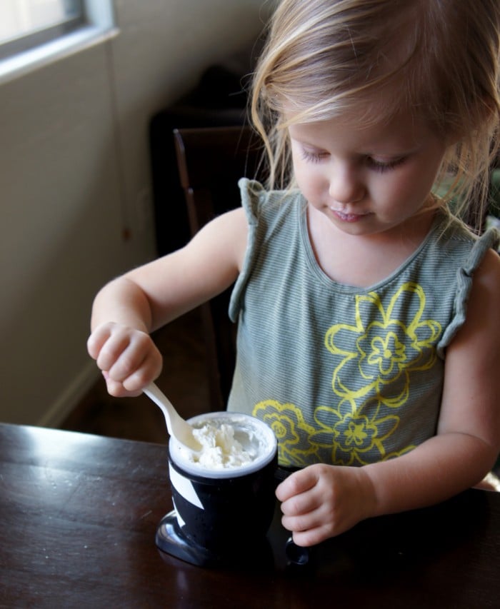 A little girl eating ice cream with a spoon