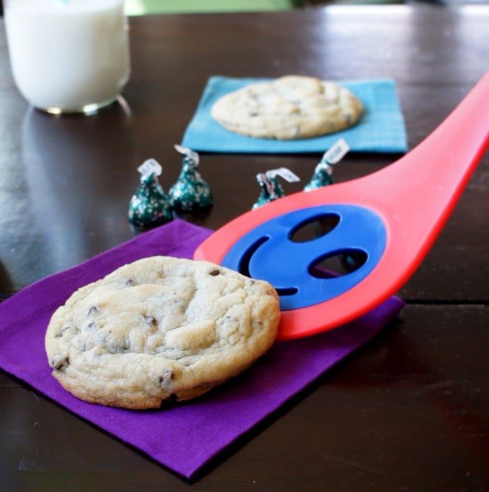 A cookie being place on a napkin with a smiley faced spatula