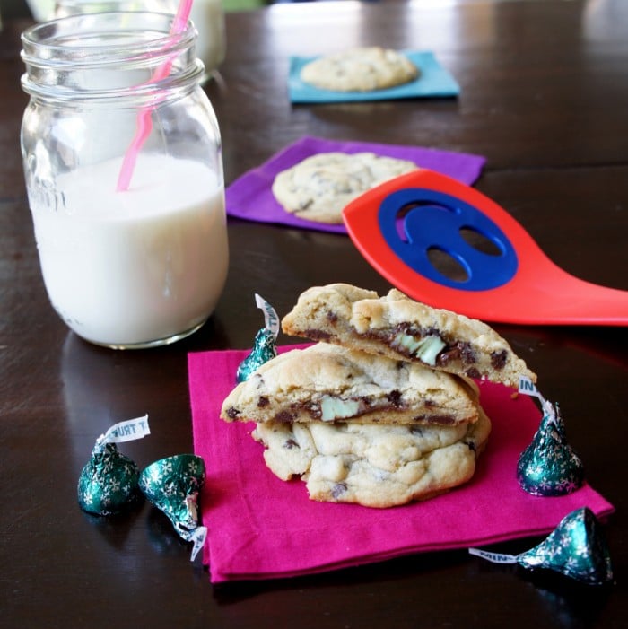 Mint Truffle Stuffed Chocolate Chip Cookies stacked on top of each other on a napkin next to a glass of milk