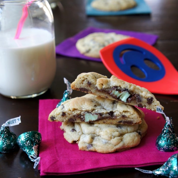 Mint Truffle Stuffed Chocolate Chip Cookies stacked on top of each other on a napkin next to a glass of milk