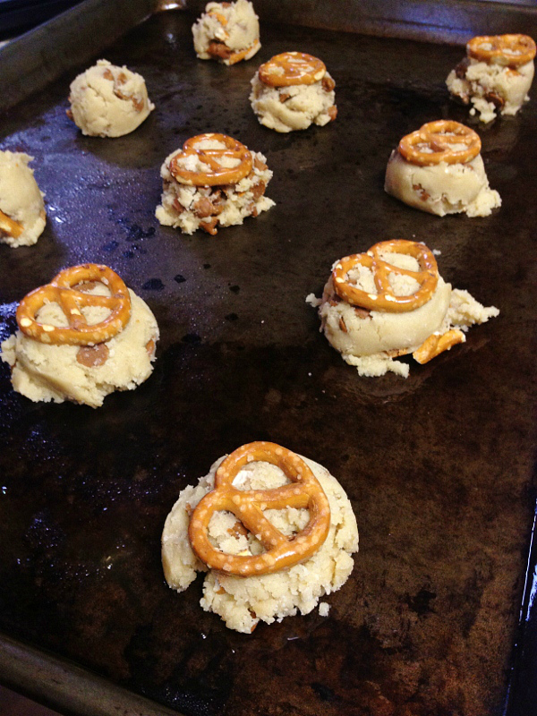 A pan with raw cookie dough balls and a pretzel on top of each