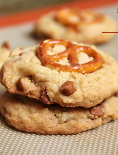 A close up of two cookies on top of each other with cinnamon chips and a pretzel on top