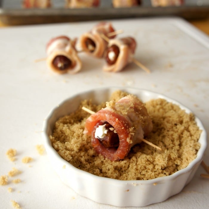 A small bowl with brown sugar demonstrating how to roll a bacon wrapped date in it