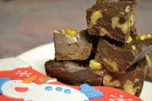 A close up of chocolate fudge squares with nuts stacked in a pile