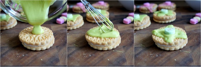 A mini whisk spreading melted green colored chocolate on top of a vanilla cookie 