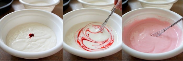 A bowl of white frosting with red dye being mixed into