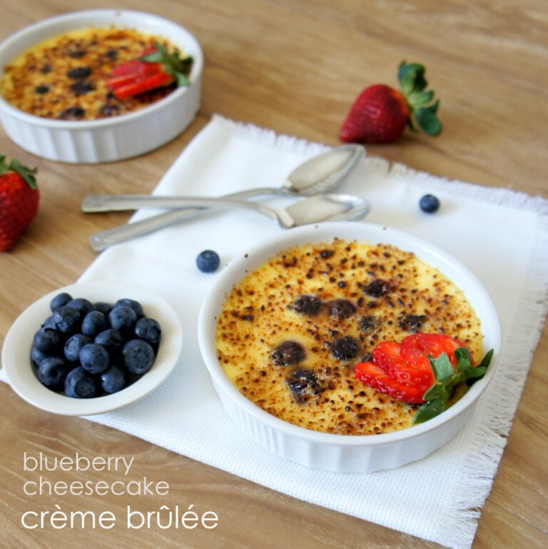 A bowl of Blueberry Cheesecake Creme Brûlée displayed on a table next to a bowl of blueberries
