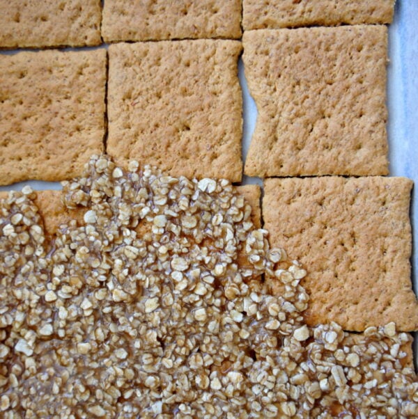 Graham cracker squares being topped with oats and toffee