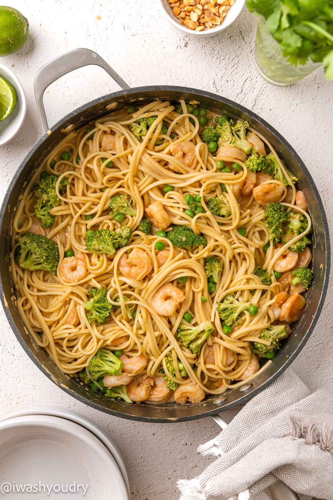 pot full of noodles with shrimp, broccoli, peas.