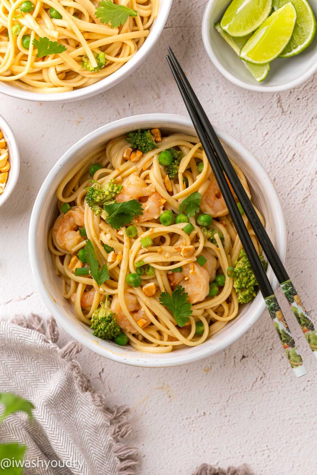 white bowl with chopsticks resting on edge, bowl filled with noodles and shrimp.